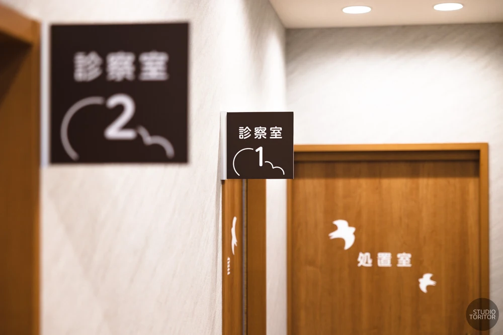 分かりやすい案内表示が施された診察室・処置室のドアサイン。クリニック内装撮影事例。