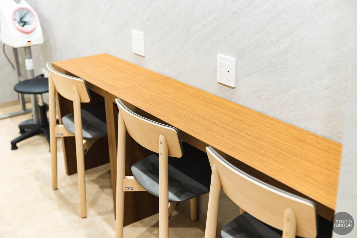 充電用コンセントが完備された待合室のカウンター席と自動血圧計。クリニック撮影事例。