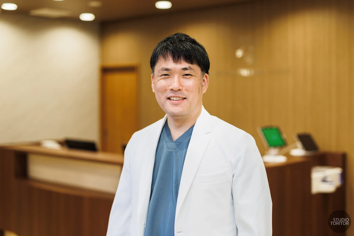 受付前で撮影した医師(院長)の笑顔のプロフィール写真。ホームページ用写真撮影事例。